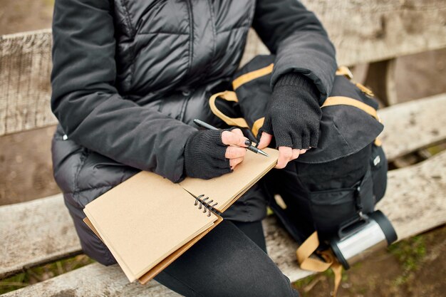 Femme de voyage avec chapeau rouge en veste noire, écrire sur un cahier, prendre des notes