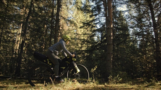 La femme voyage en cyclotourisme en terrain mixte avec bike bikepacking. Le voyage du voyageur avec des sacoches de vélo. Parc forestier magique.