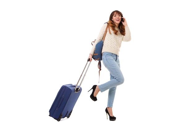 Une femme de voyage souriante qui marche et parle au téléphone portable.