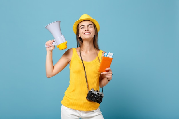 Femme de voyage en vêtements décontractés jaunes et chapeau tenant un appareil photo mégaphone de billets sur bleu