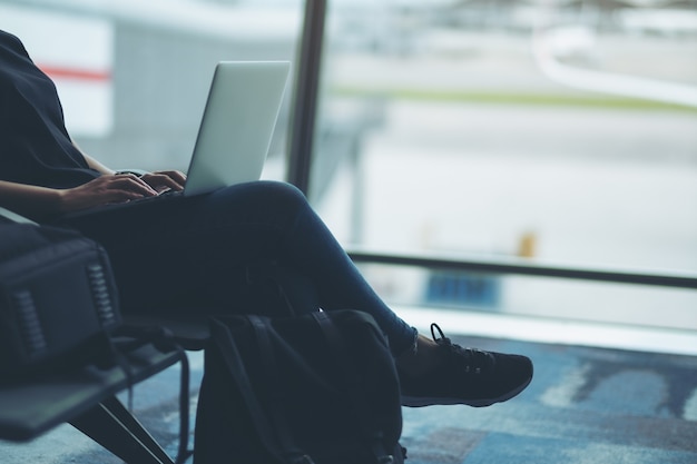 Une femme voyageant à l'aide d'un ordinateur portable alors qu'elle était assise à l'aéroport