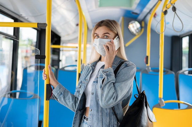 Femme voyageant en bus public parlant au téléphone tout en portant un masque médical pour se protéger