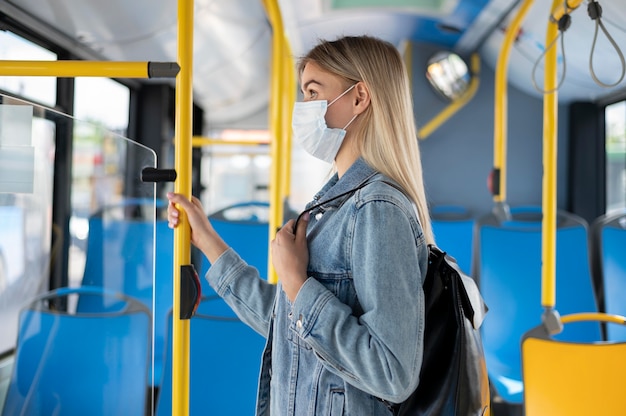 Femme voyageant en bus public et portant un masque médical pour se protéger