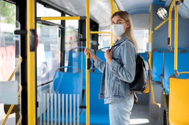 Photo femme voyageant en bus public et portant un masque médical pour se protéger