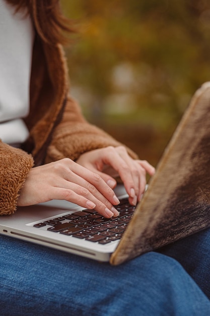 femme voyageant en train de taper sur le clavier d'un ordinateur portable tout en travaillant sur un projet à distance dans la nature en automne