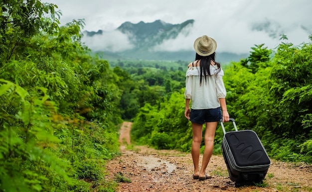 femme voyageur en arrière sa maison. femme portant des bagages