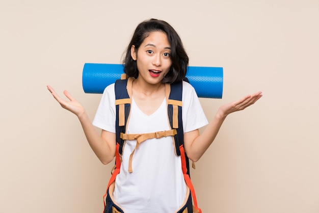 Femme voyageur asiatique sur mur isolé avec une expression faciale choquée