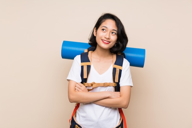 Femme voyageur asiatique sur mur isolé, levant en souriant