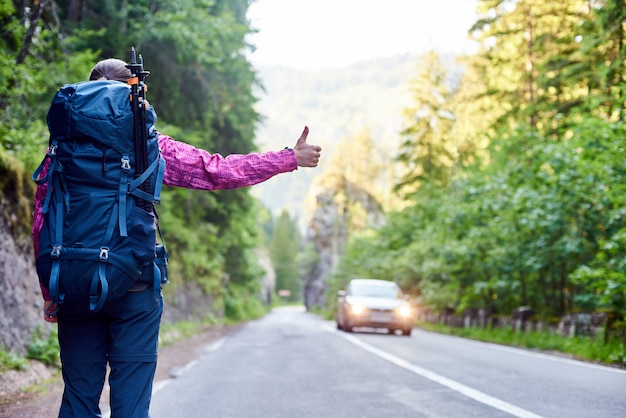 Femme de voyageur attrapant une voiture sur la route dans la gorge de Bicaz, Roumanie