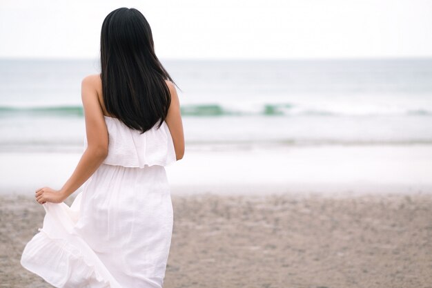 Femme de voyageur courir sur la plage de la mer