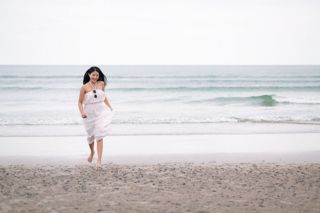 Femme de voyageur courir sur la plage de la mer