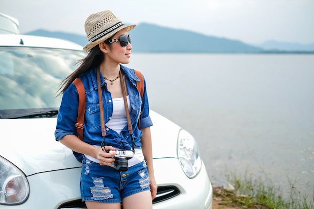 femme de voyageur debout près de la voiture et en regardant la vue sur la nature près du lac