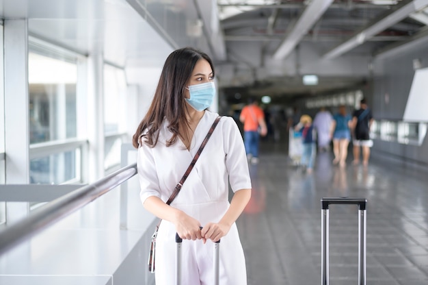 Une femme voyageur porte un masque de protection à l'aéroport international, voyage sous la pandémie de Covid-19,