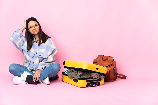 Femme de voyageur avec une valise assis sur le sol ayant des doutes