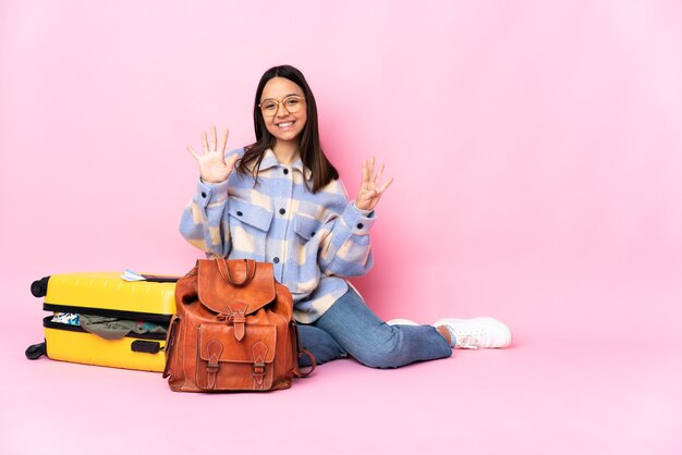 Femme de voyageur avec une valise assis sur le sol en comptant neuf avec les doigts