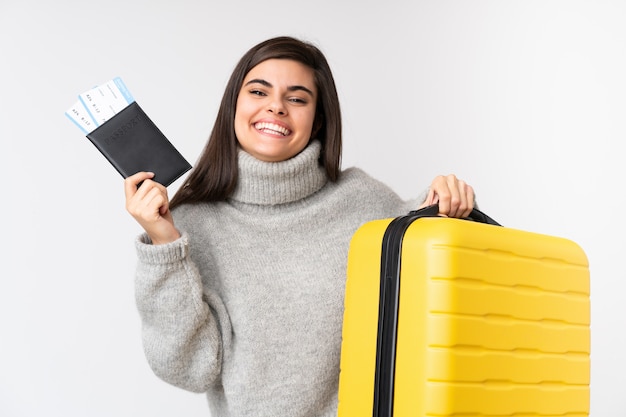 Femme voyageur avec une valise sur un mur blanc isolé