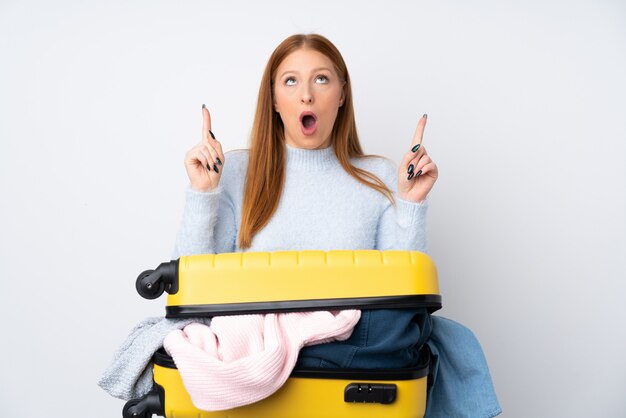 Femme de voyageur avec une valise pleine de vêtements pointant avec l'index une excellente idée