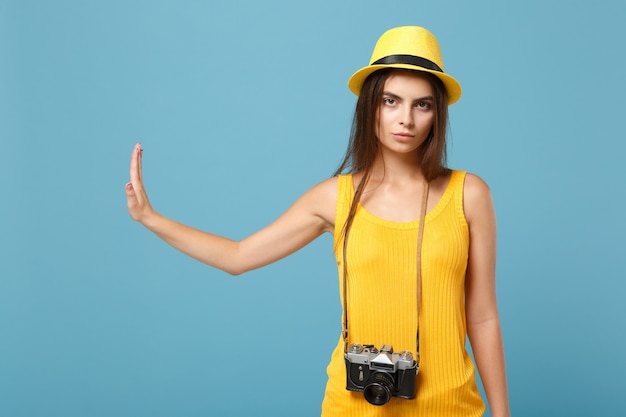 Photo femme de voyageur en vêtements décontractés d'été jaune et chapeau avec appareil photo sur bleu