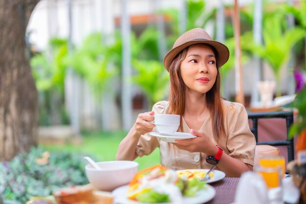 Femme voyageuse asiatique mangeant un petit-déjeuner buffet au restaurant de l'hôtel dans une zone extérieure avec café