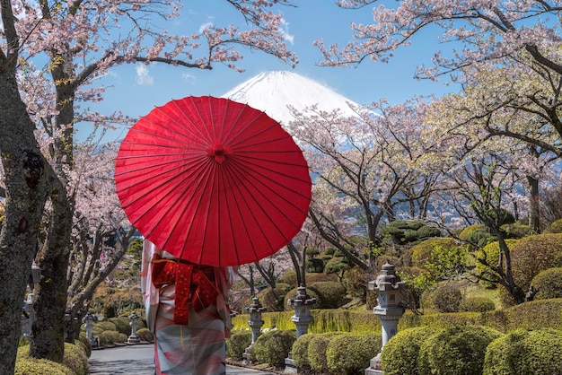 Femme voyageuse asiatique en robe kimono traditionnelle et parapluie rouge marchant avec la montagne Fuji