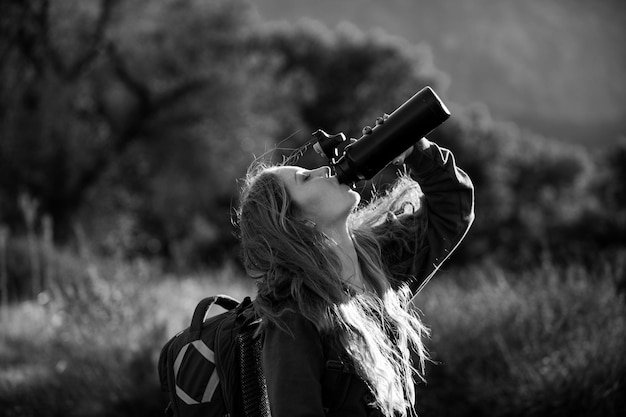 Une femme voyageuse boit de l'eau une randonneuse avec sac à dos à une fille de montagne en randonnée sur une colline à la vue panoramique po