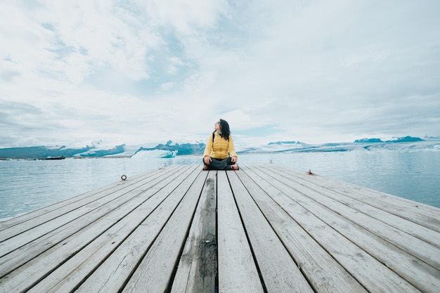 Femme voyageuse se reposant sur une jetée tranquille près de Jokursarlon arrière-plans du glacier scène de paysageLiberté liberté et concept de paysageVue sauvage naturelleVacances d'aventure mode de vie sain sac à dos