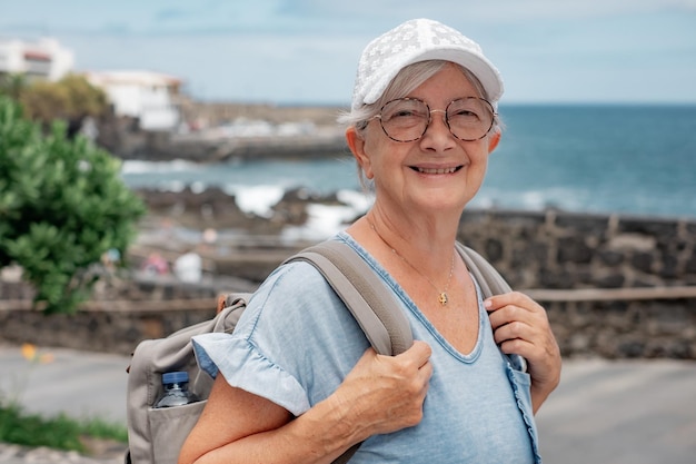 Femme voyageuse senior heureuse et détendue avec une casquette blanche marchant à l'extérieur en mer