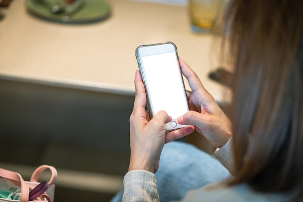 Femme vue arrière en gros plan à l'aide d'un smartphone avec un écran vide pour maquette