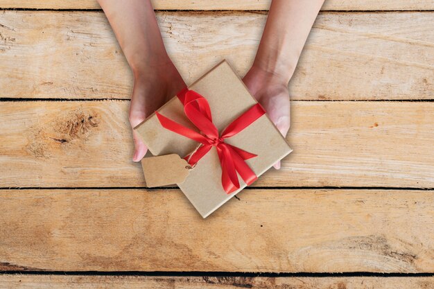 femme vue de dessus main tenant la boîte de cadeau sur la table en bois.