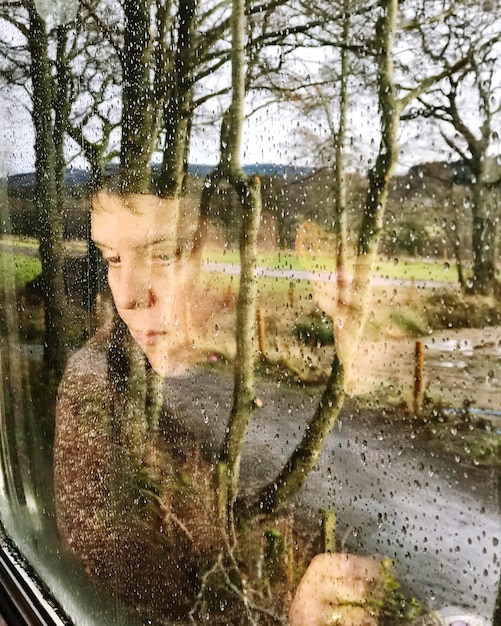 Photo femme vue à travers une fenêtre humide pendant la saison des pluies