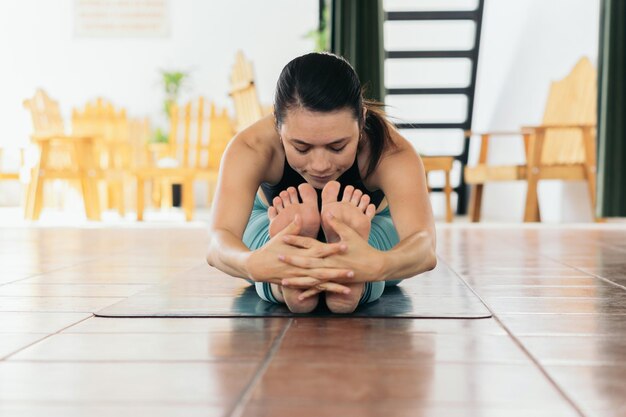 Photo une femme avec les yeux fermés assise sur le sol à la maison effectuant des étirements de jambe