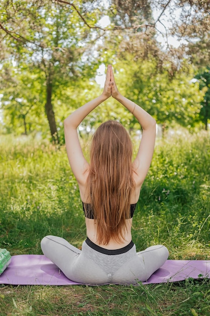 Femme de yoga sur l'herbe verte fille se détend sur le terrain Femme de yoga dans un parc verdoyant fille faisant de la gymnastique à l'extérieur