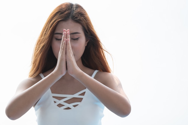 Femme de yoga méditant avec les mains jointes sur fond blanc.