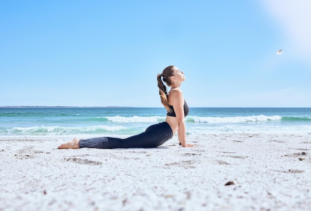 Femme de yoga zen et étirement sur la plage pour une détente ou une méditation saine Exercice d'équilibre de forme physique Entraînement de chakra et état d'esprit pilates pour la liberté de bien-être sur le sable de l'océan avec le calme de la nature ou l'entraînement