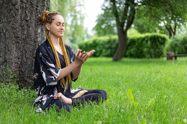 Femme yogi avec des dreadlocks pratiquant la pose de Siddhasana Ardha Padmasana Lotus