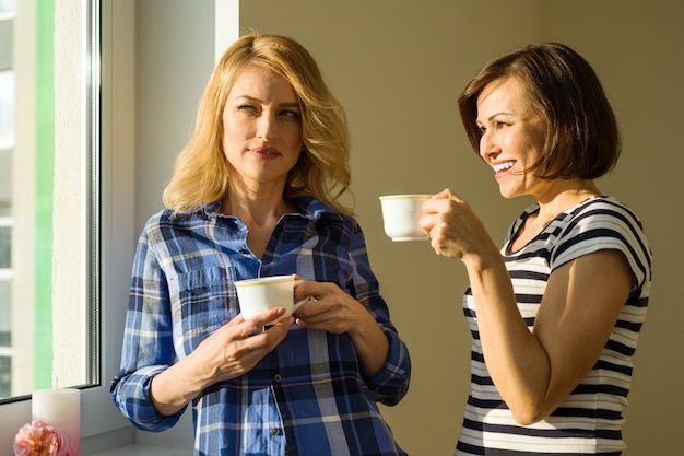 Les femmes adultes boivent du café parlent rire