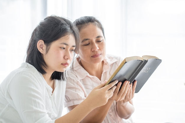 Les femmes adultes lisent la Sainte Bible et partagent l'évangile avec les jeunes. Les livres de la Bible, Concepts du christianisme.