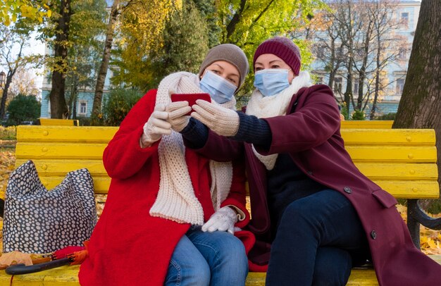 Femmes adultes portant des masques faciaux prenant un selfie