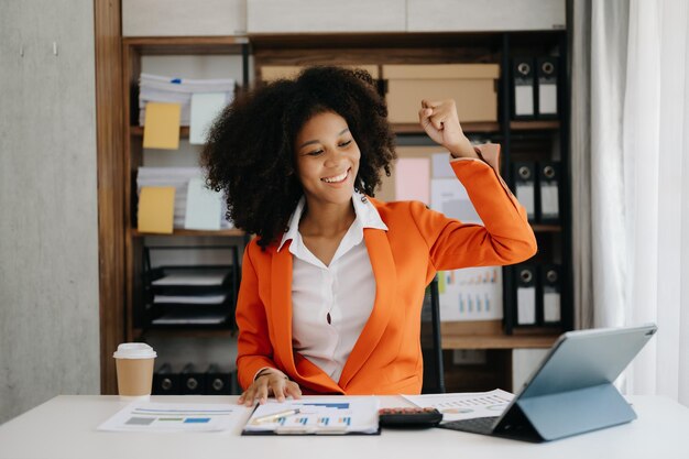 Les femmes d'affaires africaines sont enchantées et heureuses du travail qu'elles font sur leur tablette portable et prennent des notes au bureau à domicile