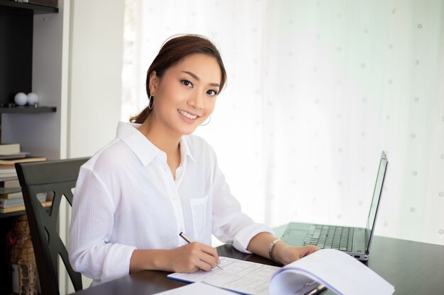 Femmes d&#39;affaires asiatiques à l&#39;aide de cahier et souriant heureux de travailler