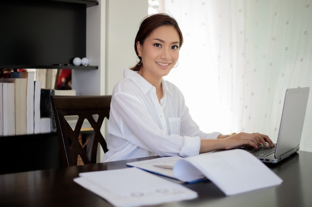 Femmes d&#39;affaires asiatiques utilisant un ordinateur portable et souriant heureux pour travailler