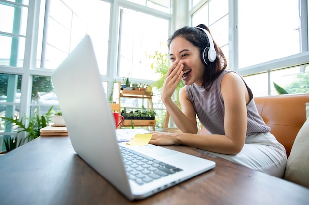 Les femmes d'affaires asiatiques utilisent des ordinateurs portables et portent des écouteurs pour les réunions en ligne et le travail à domicile.