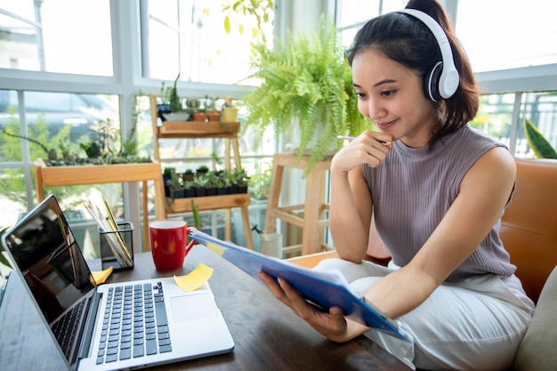 Les femmes d'affaires asiatiques utilisent des ordinateurs portables et portent des écouteurs pour les réunions en ligne et le travail à domicile.