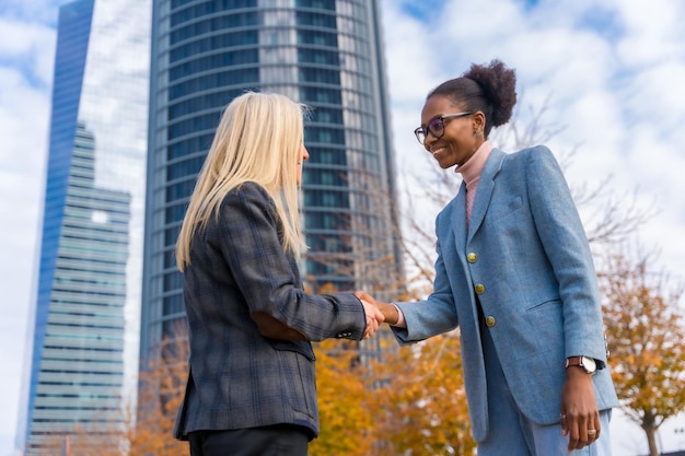 Femmes d'affaires et cadres multiethniques d'âge moyen saluant en se serrant la main pendant la pause de travail