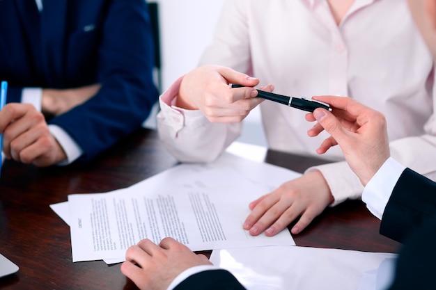 Femmes d'affaires donnant un stylo à un homme d'affaires pour la signature d'un contrat.