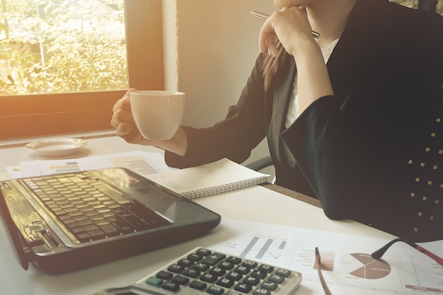 Femmes d&#39;affaires gros plan tenant le café avec du papier écrit au graphique.