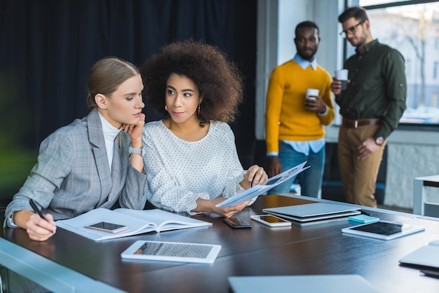 Des femmes d'affaires multiculturelles qui regardent des documents au bureau.