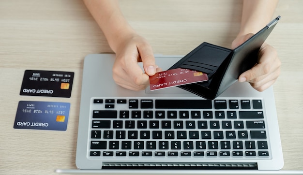 les femmes d'affaires sortent les cartes de crédit de leur poche pour faire des achats en ligne sur un ordinateur portable à la maison