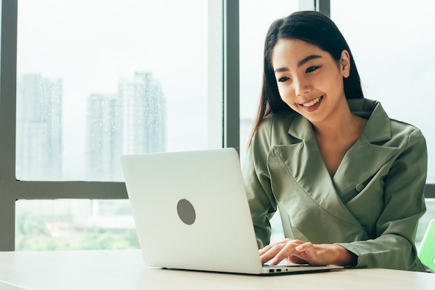 Les femmes d'affaires sourient et utilisent l'ordinateur au bureau de la fenêtre Marché boursier commercial