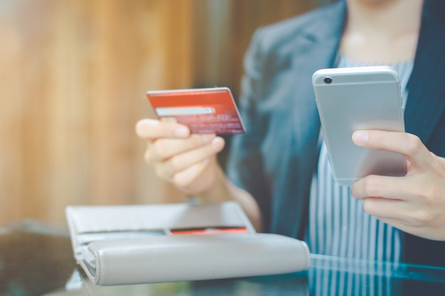 Les femmes d&#39;affaires utilisent un téléphone portable pour faire leurs achats en ligne via des cartes de crédit.